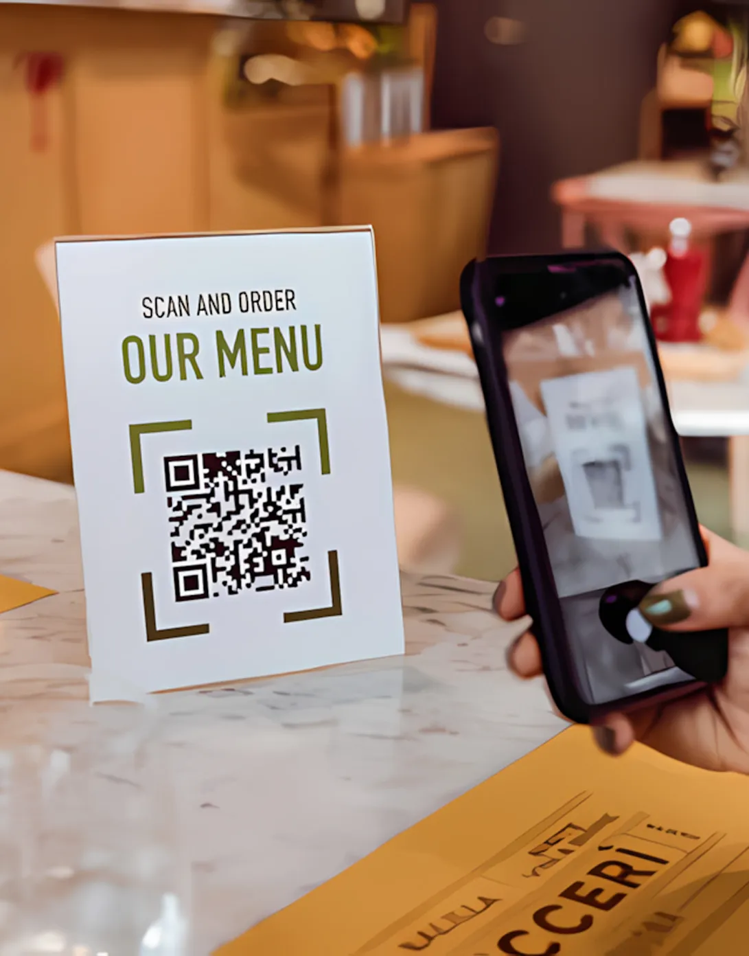Person scanning a QR code on a table tent that says 'Scan and order our menu' using a smartphone.